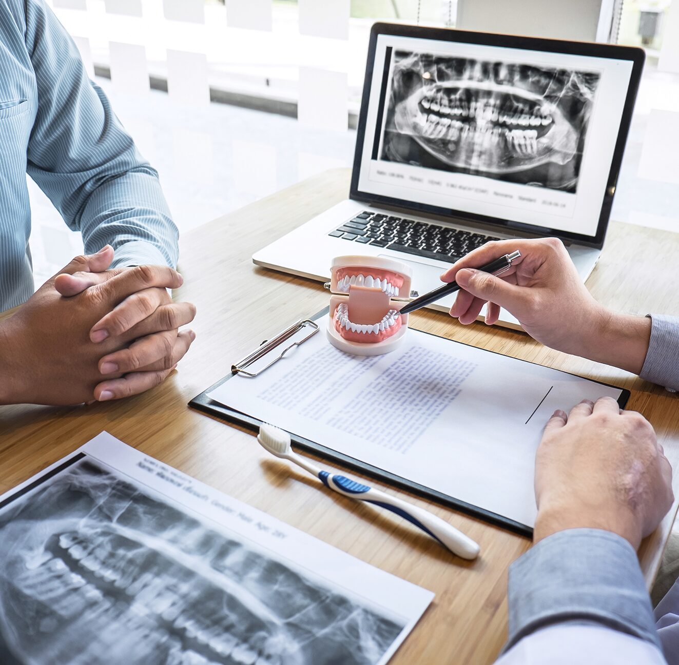 Two clinicians reviewing a panoramic dental radiograph across a desk